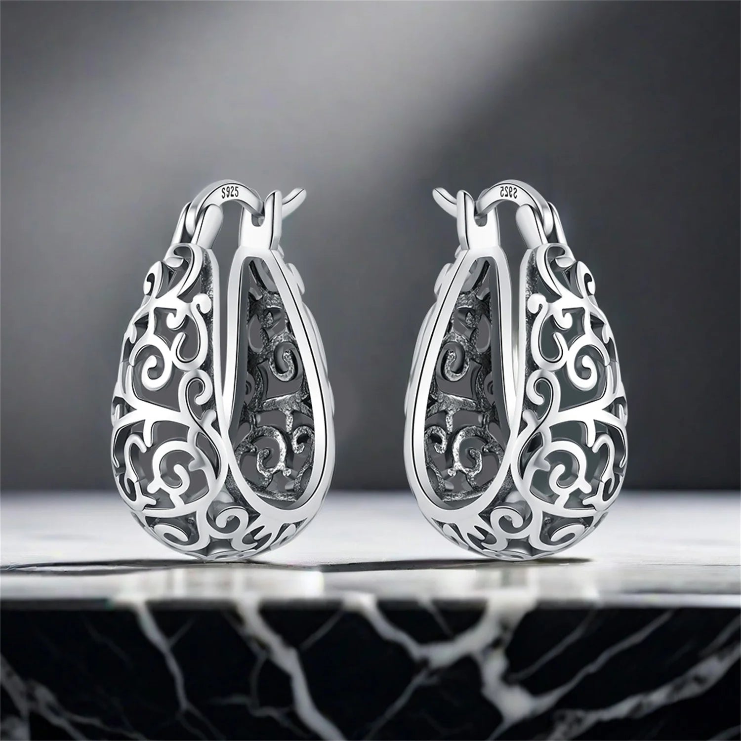Side angle of 925 sterling silver vine hoop earrings under studio lighting